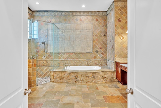 bathroom featuring vanity, independent shower and bath, and tile walls