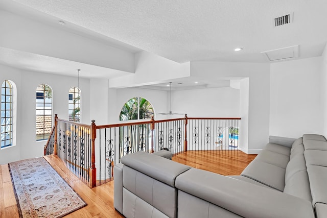 living room with ceiling fan, a textured ceiling, and light hardwood / wood-style flooring