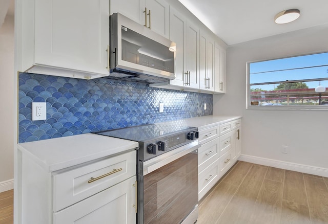 kitchen with stainless steel appliances, light hardwood / wood-style flooring, and white cabinets