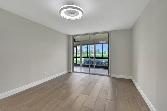 unfurnished room with hardwood / wood-style flooring and floor to ceiling windows