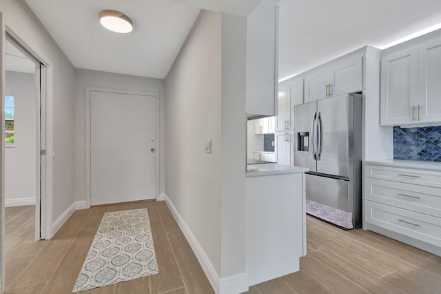 kitchen with decorative backsplash, stainless steel fridge with ice dispenser, light hardwood / wood-style flooring, and white cabinets