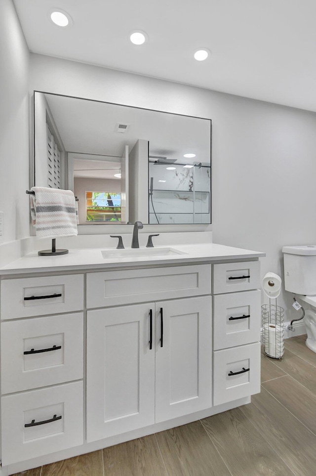 bathroom featuring vanity, toilet, hardwood / wood-style flooring, and walk in shower