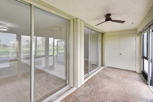 unfurnished sunroom featuring ceiling fan