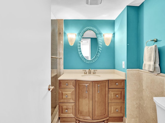 bathroom featuring toilet, vanity, and tile walls