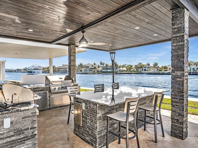 view of patio / terrace with an outdoor bar, a grill, and a water view