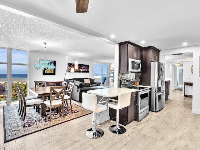 2200 S Ocean Blvd Unit 806, Delray Beach, FL 33483 - kitchen featuring stainless steel appliances, dark brown cabinetry, light wood-style floors, light countertops, and decorative backsplash