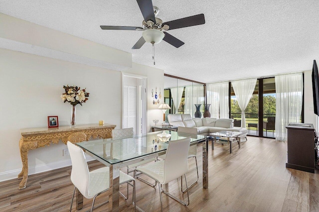 dining space featuring wood-type flooring, a wall of windows, a textured ceiling, and ceiling fan