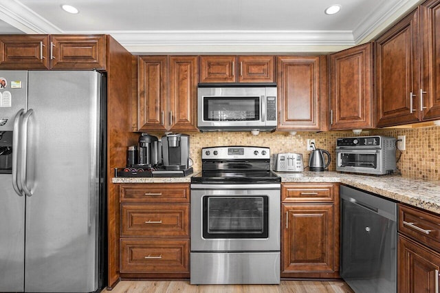 kitchen featuring light wood-type flooring, light stone counters, decorative backsplash, ornamental molding, and appliances with stainless steel finishes