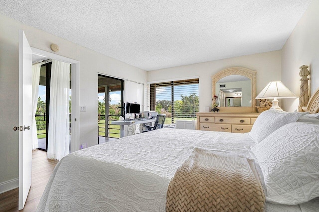 bedroom featuring access to outside, hardwood / wood-style flooring, and a textured ceiling