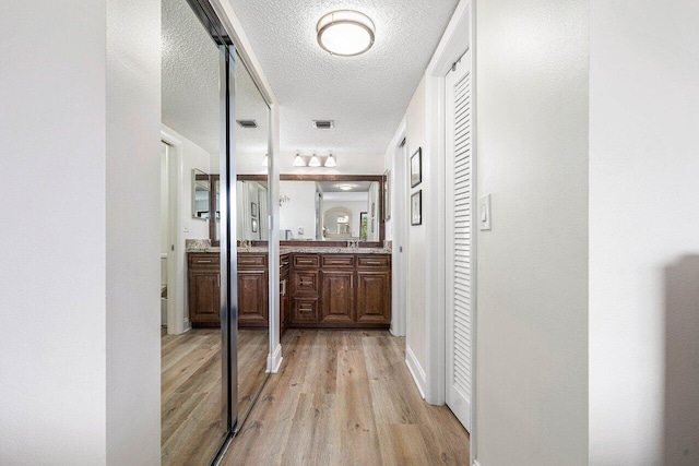 hallway featuring light wood-type flooring and a textured ceiling