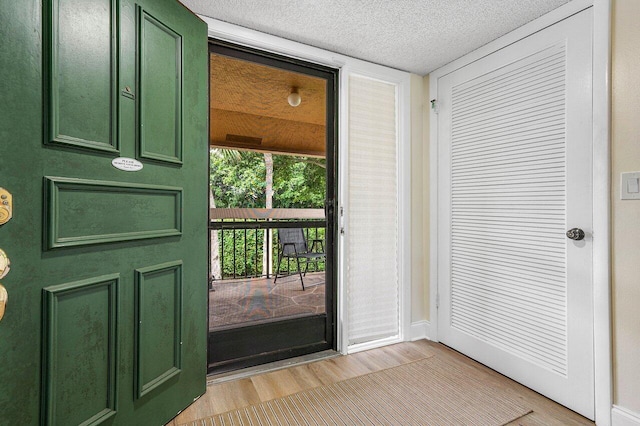 doorway featuring light hardwood / wood-style flooring and a textured ceiling