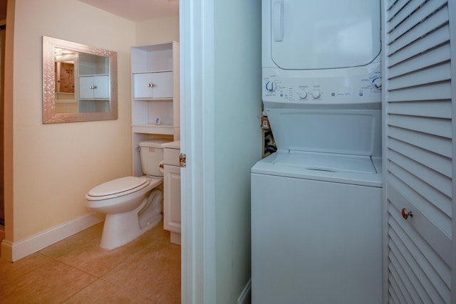 laundry area with stacked washer and dryer, baseboards, and light tile patterned floors