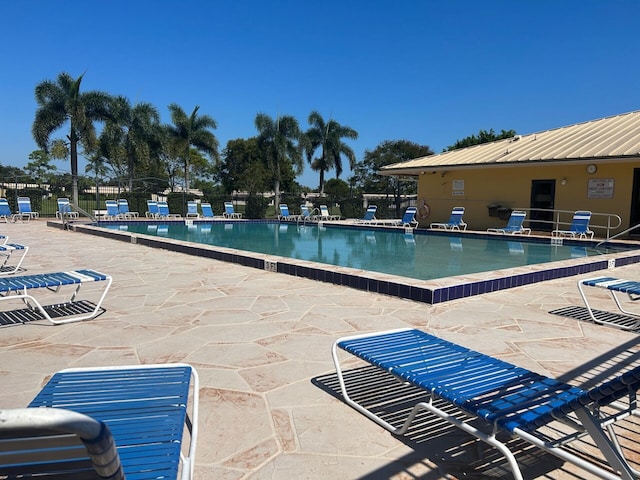 community pool with a patio area and fence