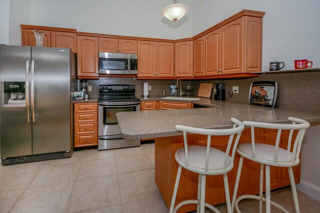 kitchen featuring decorative backsplash, stainless steel appliances, sink, a kitchen bar, and light tile patterned floors