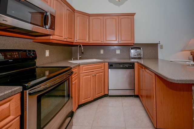 kitchen with light tile patterned floors, decorative backsplash, a peninsula, stainless steel appliances, and a sink