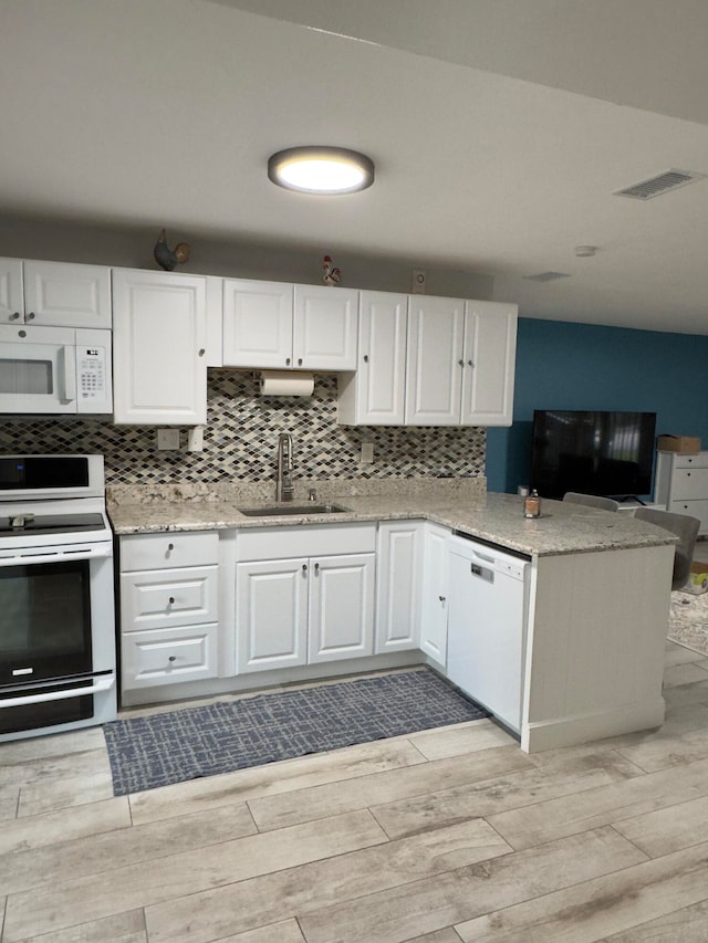 kitchen featuring white appliances, a sink, white cabinets, backsplash, and wood tiled floor