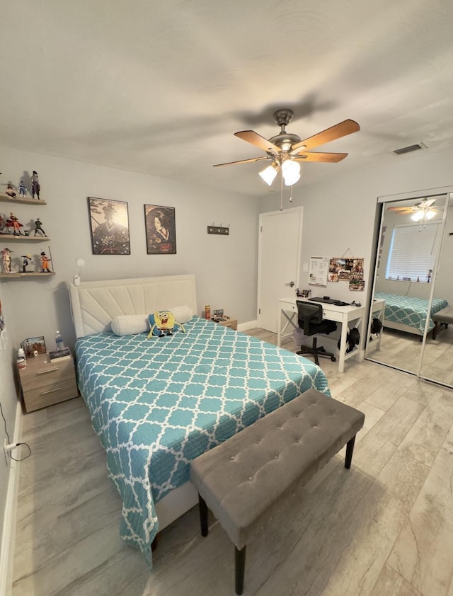 bedroom featuring light wood-type flooring, ceiling fan, visible vents, and a closet