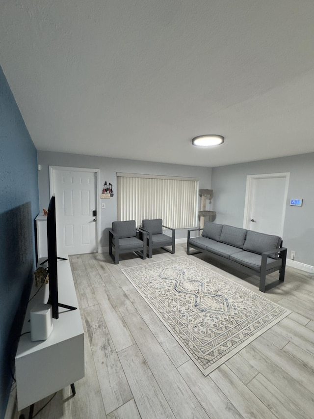 living room with a textured ceiling, baseboards, and wood finished floors