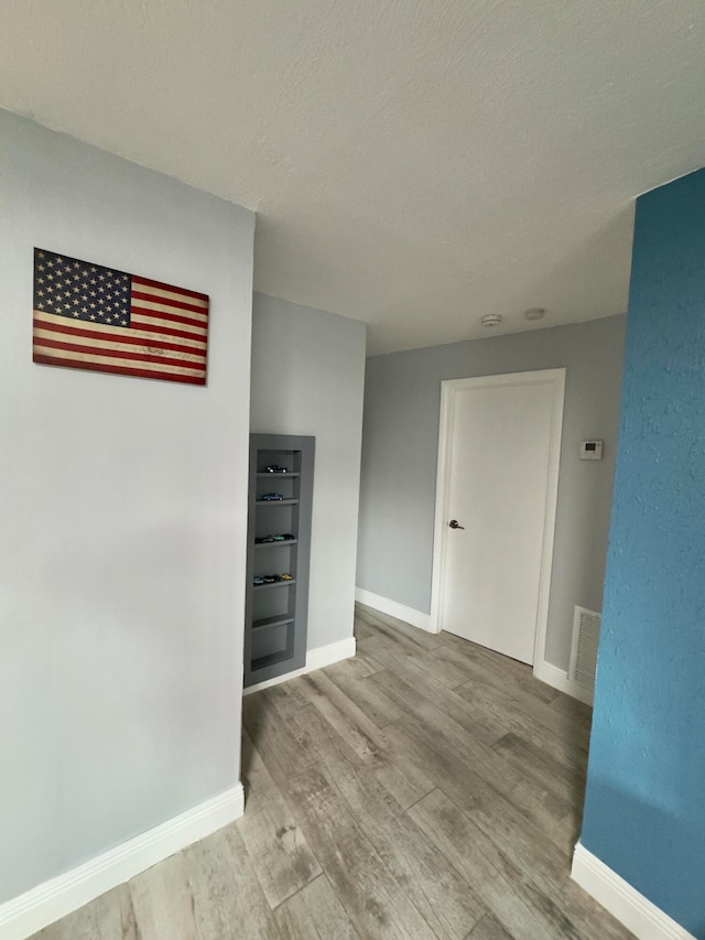 empty room with a textured ceiling and light wood-type flooring