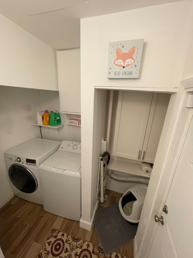 laundry area featuring light wood-type flooring, cabinet space, and washer and clothes dryer