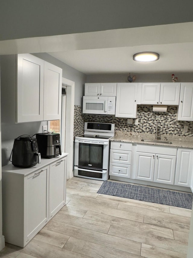 kitchen featuring white appliances, white cabinets, a sink, and light wood finished floors