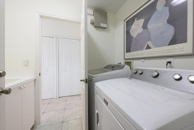 washroom with cabinets, washing machine and dryer, and light tile patterned floors