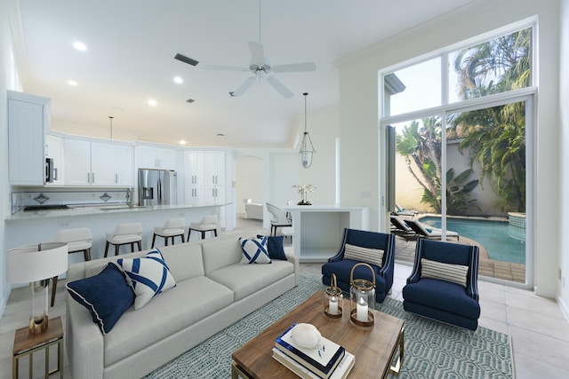 tiled living room with ceiling fan and crown molding