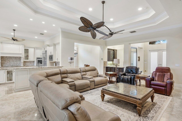 living room featuring ceiling fan, a raised ceiling, ornamental molding, and french doors