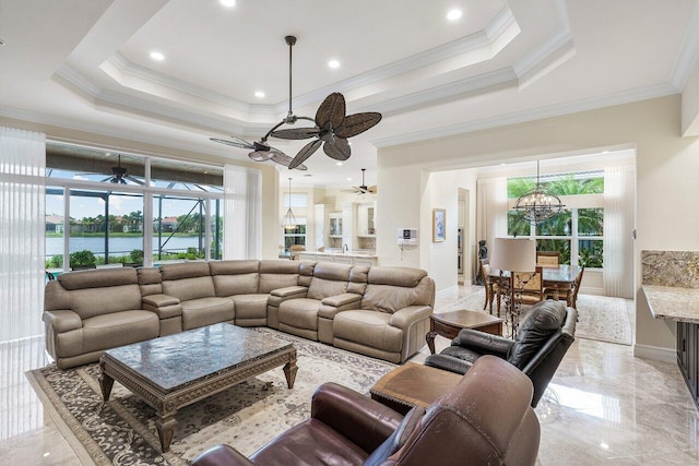 living room with a tray ceiling, a water view, ornamental molding, and an inviting chandelier