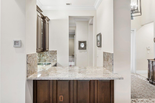 kitchen with decorative backsplash, light stone countertops, kitchen peninsula, and ornamental molding