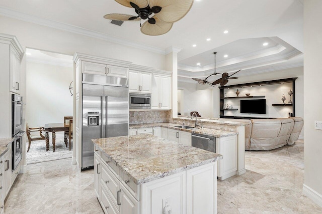 kitchen with a center island, white cabinets, sink, built in appliances, and light stone counters