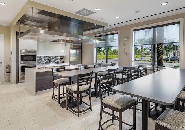 tiled dining room with plenty of natural light, ornamental molding, and sink