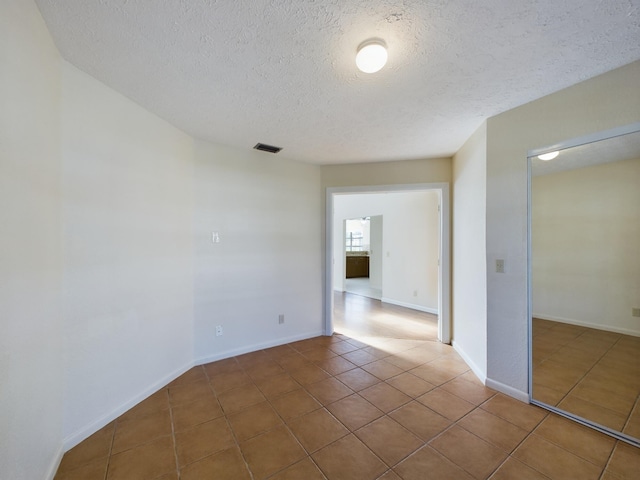 unfurnished room featuring dark tile patterned floors and a textured ceiling