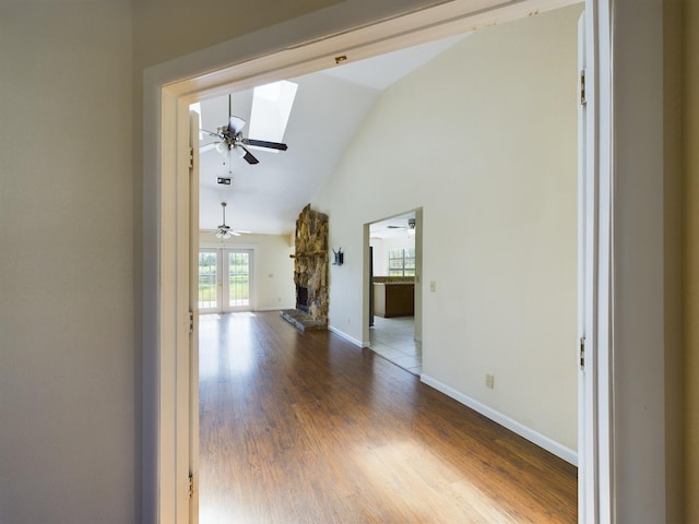 unfurnished living room with lofted ceiling with skylight, wood-type flooring, a fireplace, and ceiling fan