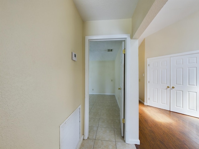 hallway featuring baseboards, visible vents, and light tile patterned flooring