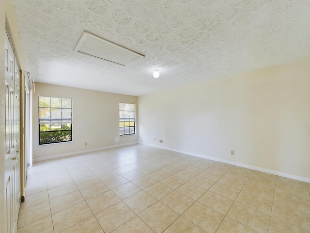 4948 SE 44th St, Okeechobee, FL 34974 - empty room featuring attic access, light tile patterned flooring, a textured ceiling, and baseboards