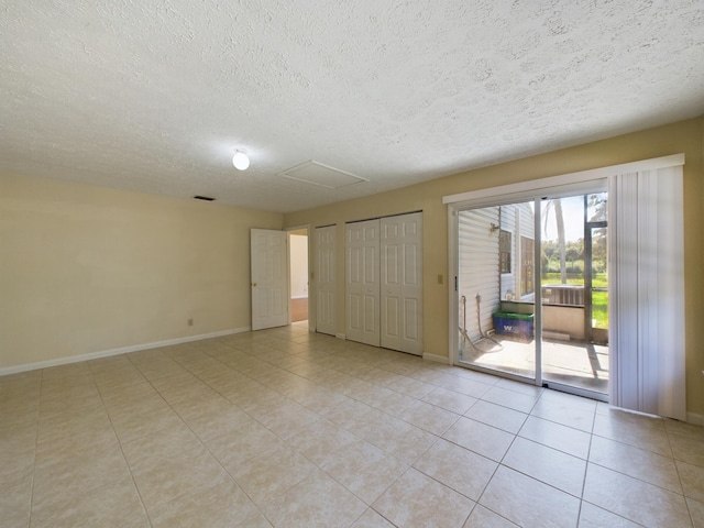 tiled empty room featuring a textured ceiling