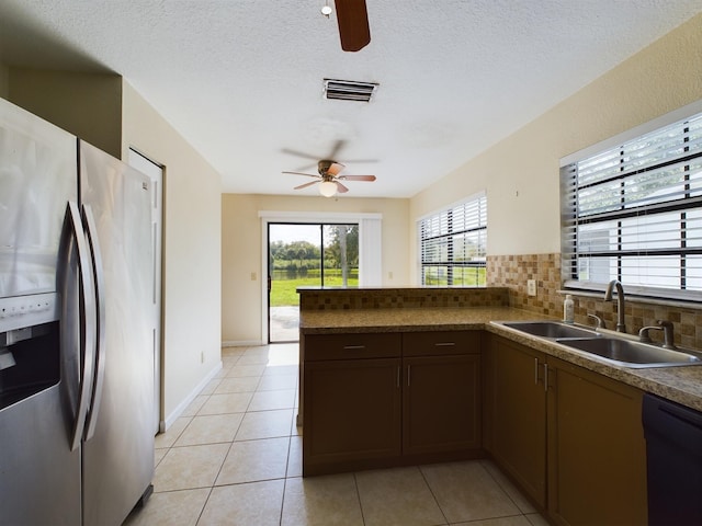 kitchen featuring black dishwasher, stainless steel refrigerator with ice dispenser, sink, light tile patterned flooring, and tasteful backsplash