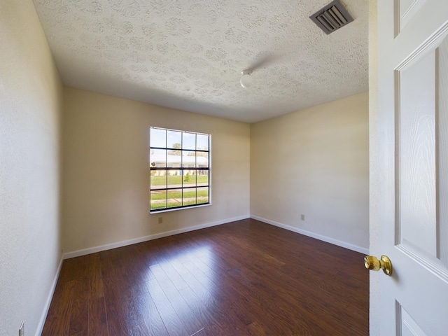 spare room featuring dark wood-type flooring and a textured ceiling