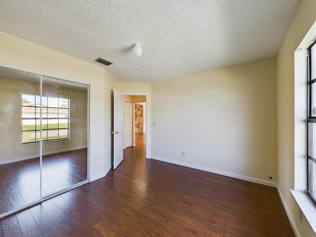 unfurnished bedroom featuring wood-type flooring, visible vents, and baseboards