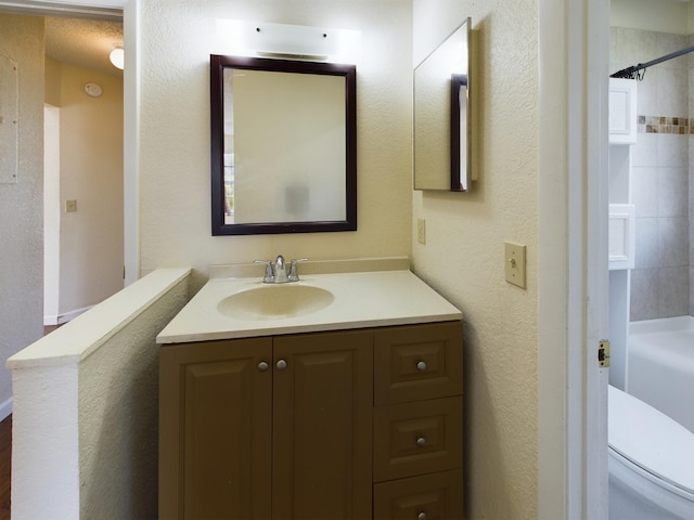 full bathroom with vanity, toilet, a textured ceiling, and tiled shower / bath