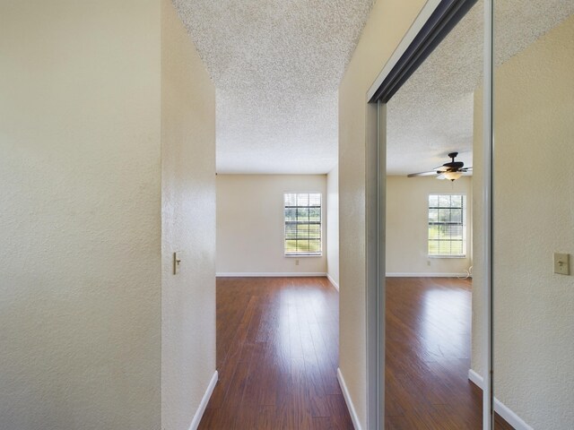 unfurnished bedroom with a closet, ceiling fan, multiple windows, and dark hardwood / wood-style flooring