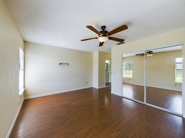 unfurnished bedroom featuring a textured ceiling, a closet, wood finished floors, and baseboards