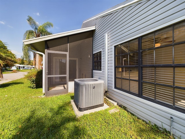 rear view of house with a yard, a sunroom, and central AC