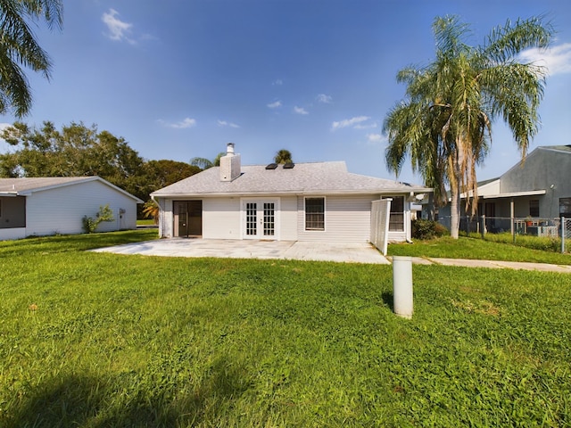 rear view of house featuring a lawn, fence, a patio, and french doors