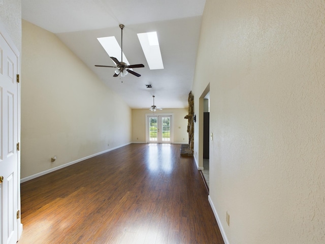 unfurnished living room featuring lofted ceiling with skylight, ceiling fan, and dark hardwood / wood-style flooring