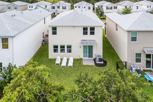 1822 Lake Cove Dr, Lake Worth Beach, FL 33460 - back of house featuring a residential view, central AC, stucco siding, and a lawn