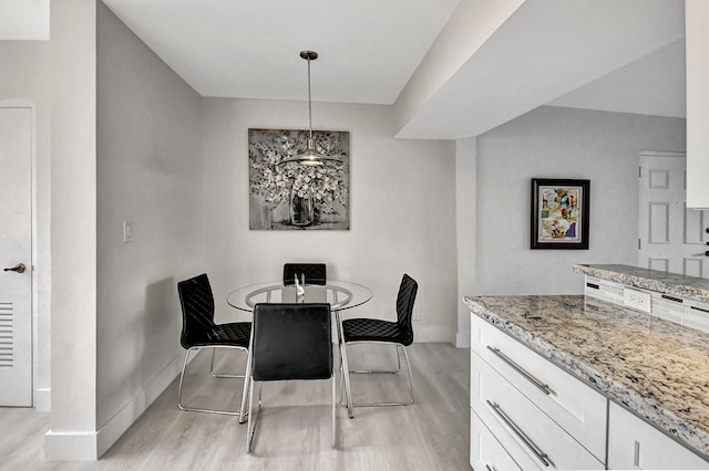 dining space featuring light wood-type flooring and a chandelier