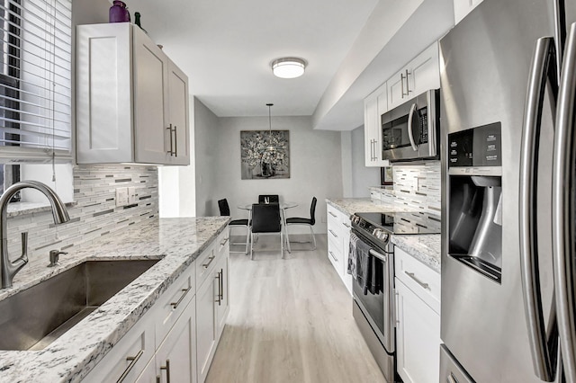 kitchen featuring sink, decorative backsplash, hanging light fixtures, appliances with stainless steel finishes, and white cabinetry