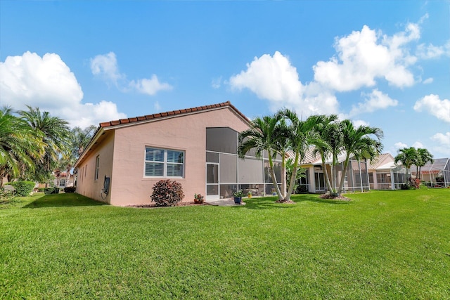 back of house featuring a lanai and a yard